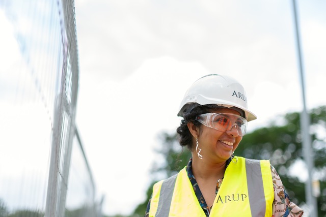 [how the initiative provides a boost for the economy] Image shows a woman in a construction hat and protective googles wearing a high vis vest, at work.